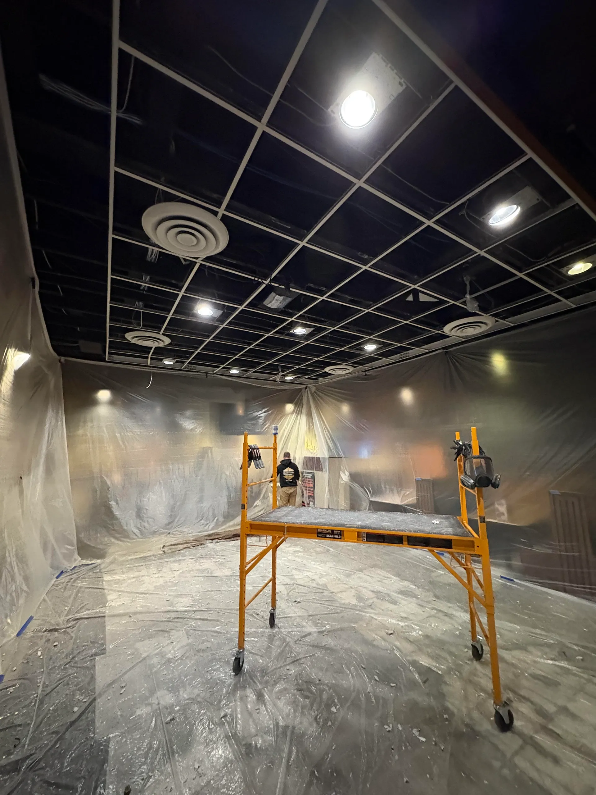 Commercial interior painting project with protective masking and plastic sheeting