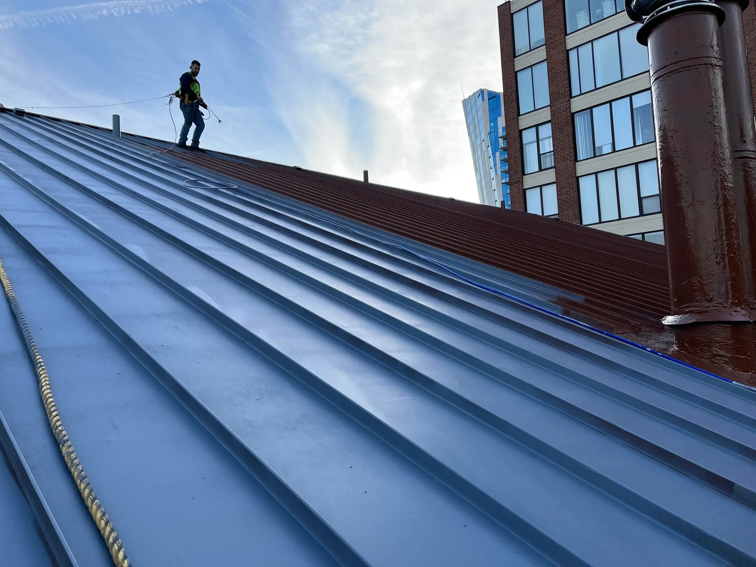 Industrial roof coating application on sloped metal roof
